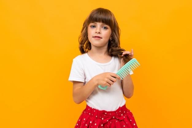 Brown-haired girl combing her hair on orange