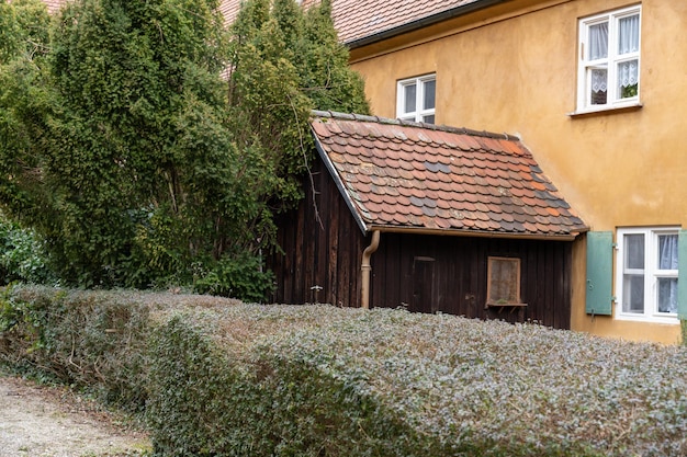 A brown house with a red roof and a shed in front of it