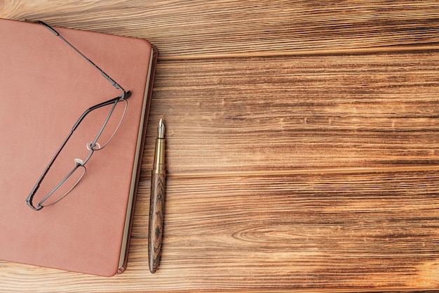 Brown notebook with fountain pen and glasses