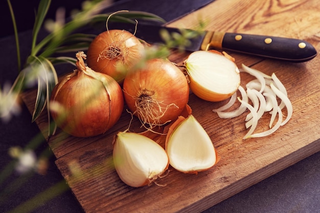 Brown onions and slices on wooden cutting boardHealthy food background