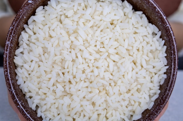 Brown plate with golden rice in the hands of a girl closeup Asian food concept