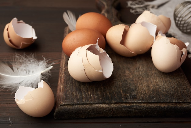 Brown raw chicken eggs, shells, cutting board and hand-held whis