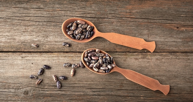 Brown raw round beans in a wooden spoon on the table