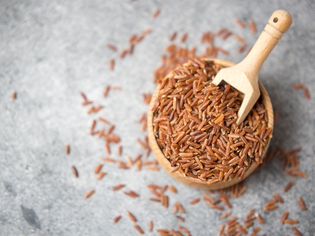 Brown rice closeup in a wooden bowl and scoop