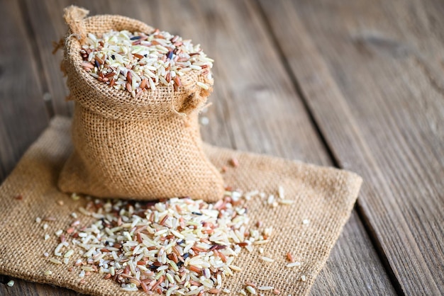 Brown rice in the sack with wooden background raw various rice color mixed thai rice for cooking food Loonzain rice brown black red white purple health food