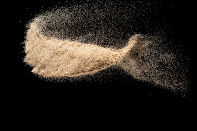 Brown sand explosion isolated on black background. Freeze motion of sandy dust splash. 