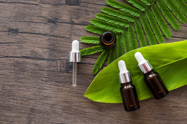 Photo brown spa aroma oil bottles on green leaf over the wooden table