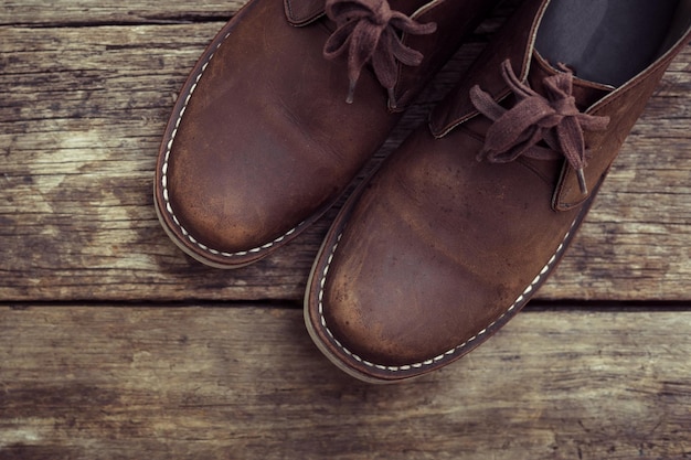 Brown stylish boots on wood background retro color