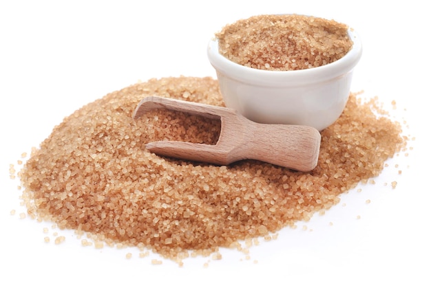 Brown sugar with wooden scoop over white background