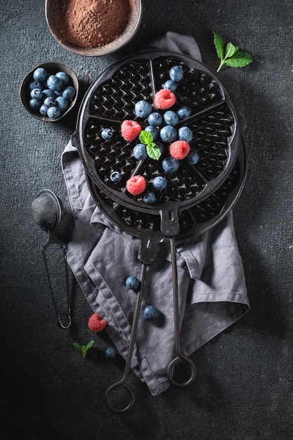 Brown and sweet dark waffles with chocolate and berry fruits