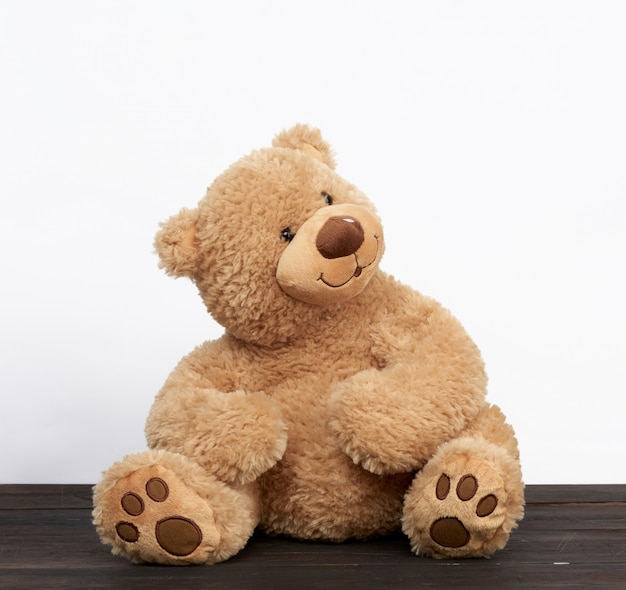 Brown teddy bear sits on a brown wooden table