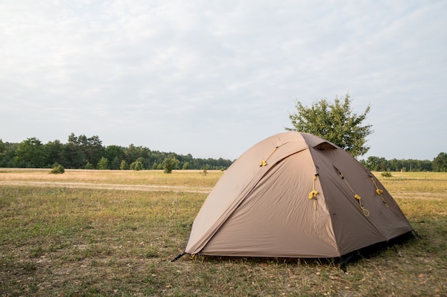 Brown tent stands on the lawn on a background of sunset