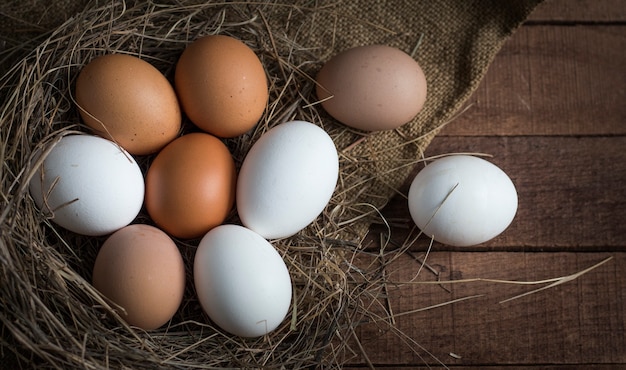 Brown and white eggs in a sleepy nest on a brown wooden background with burlap.