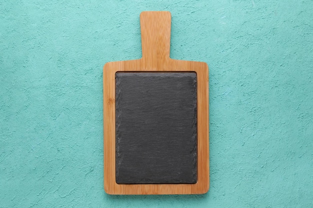 Photo brown wooden cutting board with slate stone on blue bright turquoise texture background mock up top view with copy space rustic dishes