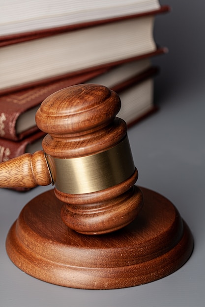 Brown wooden gavel with stack of books on gray table