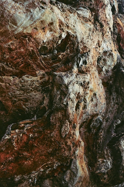 Brownblack stone wall of the cave as a background or a backdrop Vertical image