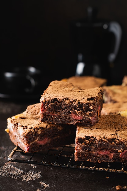 Photo brownie cheesecake cake with cherry and chocolate on a dark background. selective focus.