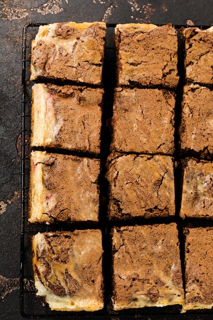 Brownie cheesecake cake with cherry and chocolate on dark background. Top view.