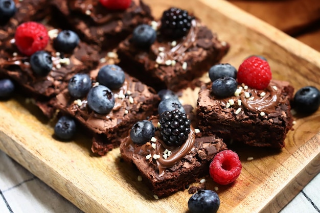 Brownie with berries and chocolate on a wooden board Homemade vegan brownies