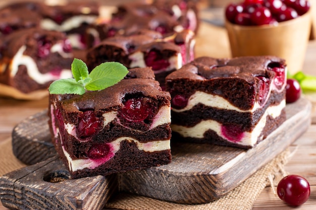 Brownie with cottage cheese and cherries on wooden table