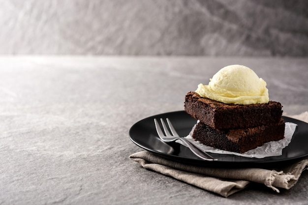 Brownie with vanilla ice cream scoop on gray stone