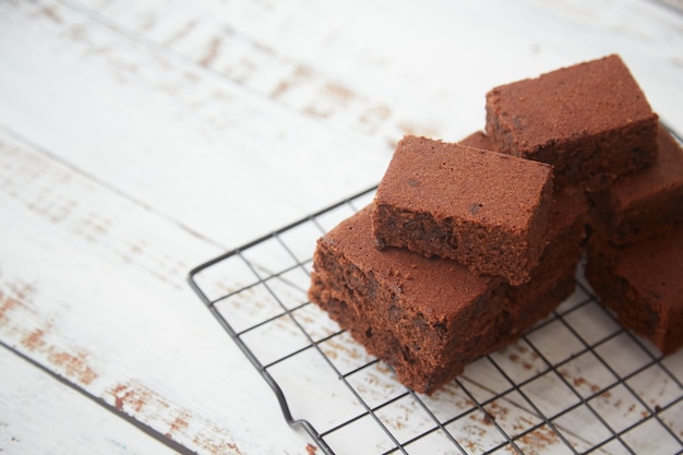 Brownies on a cooling grid on white wooden background. Copy space.