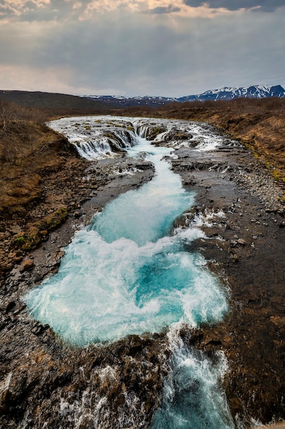 Photo bruarfoss waterfall in iceland with vibrant blue waters and a rugged landscape