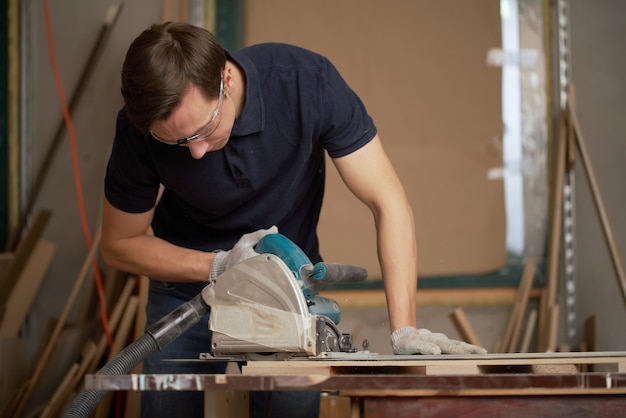 Brunet male works on jigsaw in workshop