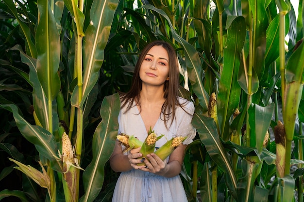 Brunette in blue dress holding corn in the field