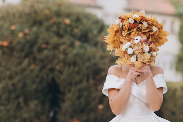 Brunette Bride in the Autumn Forest in a White Dress in a Wreath of Leaves.