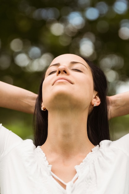 Brunette enjoying nature with her hands behind head