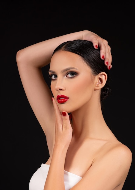 Brunette fashion model with smokey eyes and red lipstick make up on black background