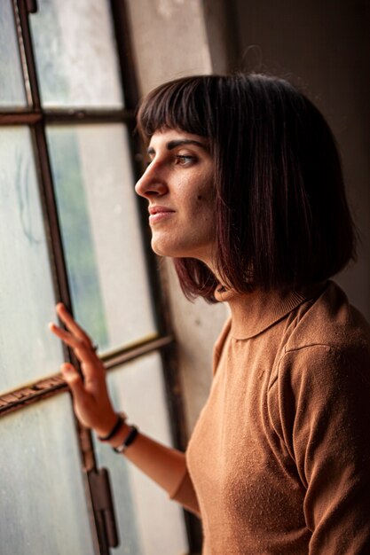 Brunette girl in front of a window looking out of the window, image in low light