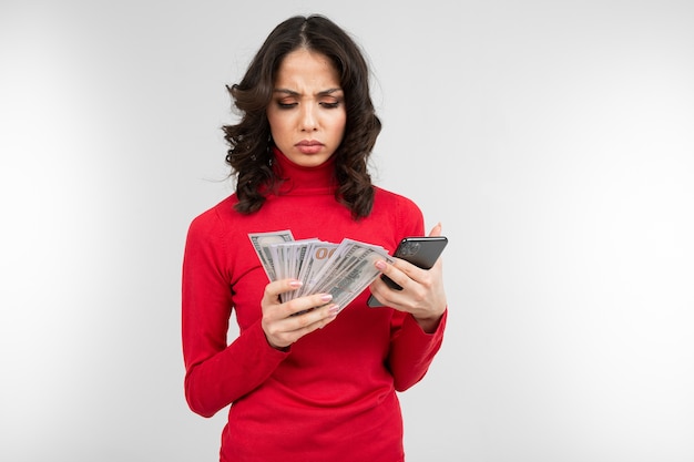 Brunette girl holds considers her earned money in her hands on a white background with copy space.