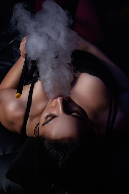 The brunette girl smokes a hookah