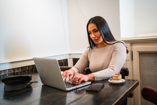 Brunette girl teleworking in a coffee shop with laptop