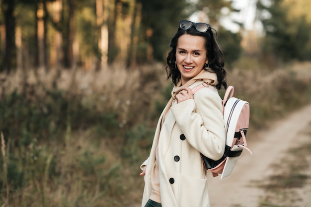 brunette girl with backpack on the forest path