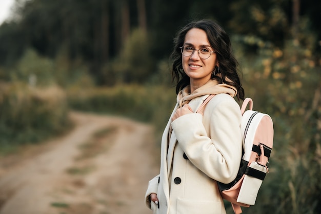 brunette girl with backpack on the forest path