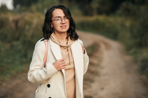 brunette girl with backpack on the forest path