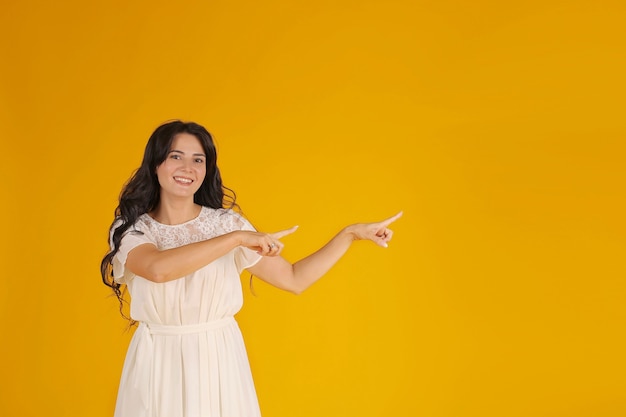 a brunette girl with long hair in a white dress shows the direction with her hands