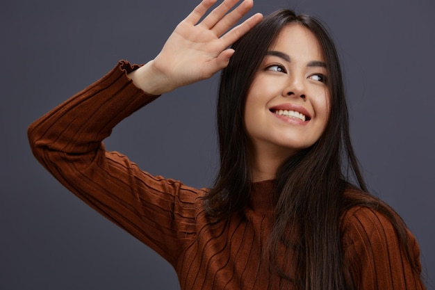 Brunette hand gestures brown sweater fashion Gray background