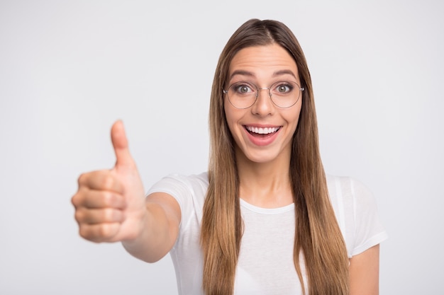 brunette lady with glasses posing against the white wall