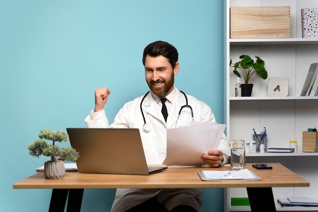 Brunette man surgeon smiling and rejoicing with documents at the hands