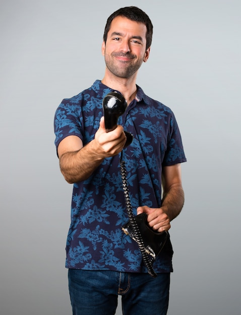 Brunette man talking to vintage phone on grey background