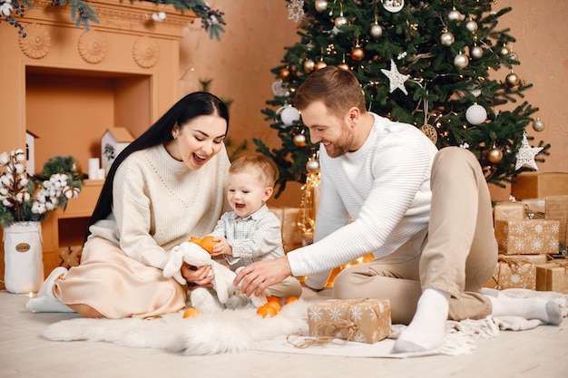 Brunette mother father and little son sitting near Christmas tree