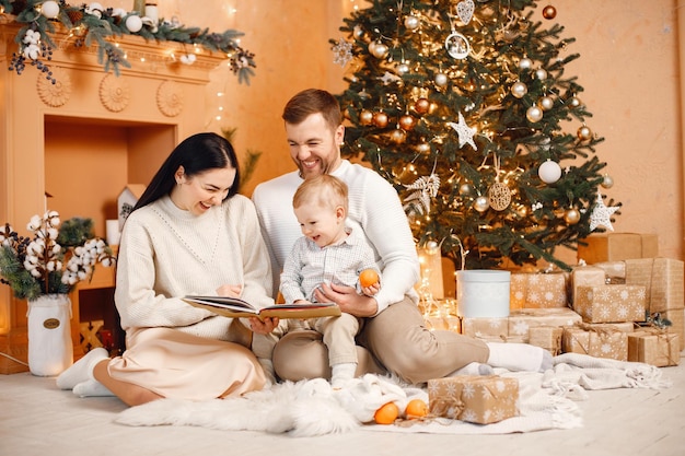 Brunette mother father and little son sitting near Christmas tree