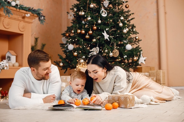 Brunette mother father and little son sitting near Christmas tree