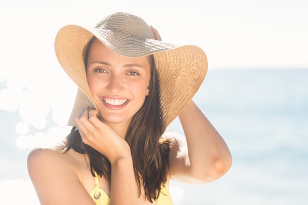 Brunette relaxing with a straw hat smiling at camera