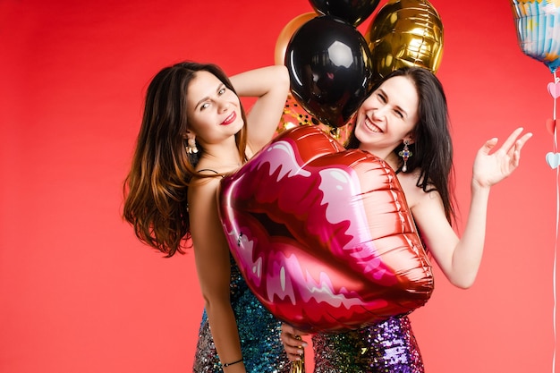 Brunette twins in black and red costumes posing at camera