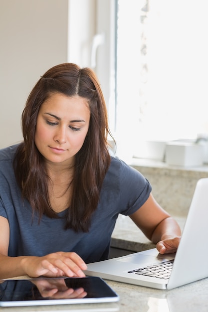 Brunette typing on the tablet pc and laptop